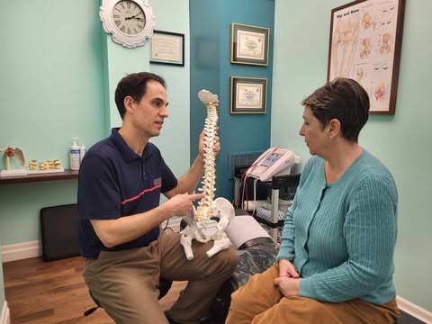 Dr Cameron holding a Spine model while showing it to a patient.