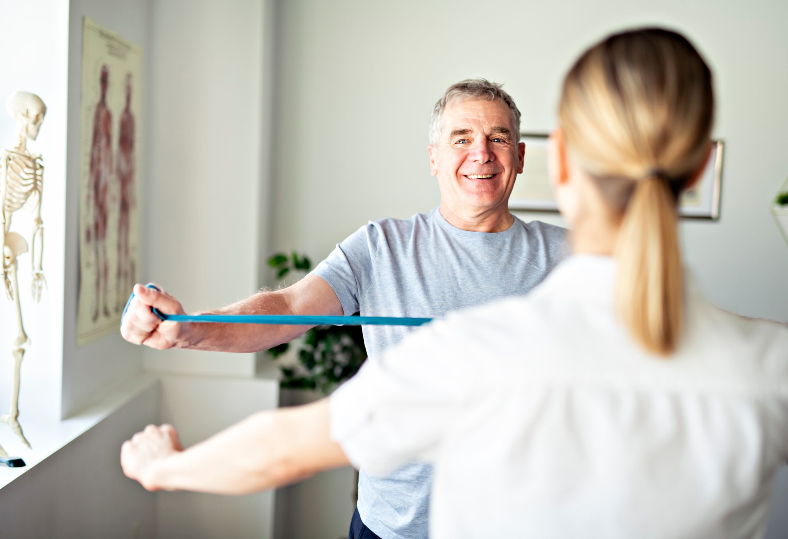 Chiropractor demonstrating to a male client how to perform physiotherapy exercise.