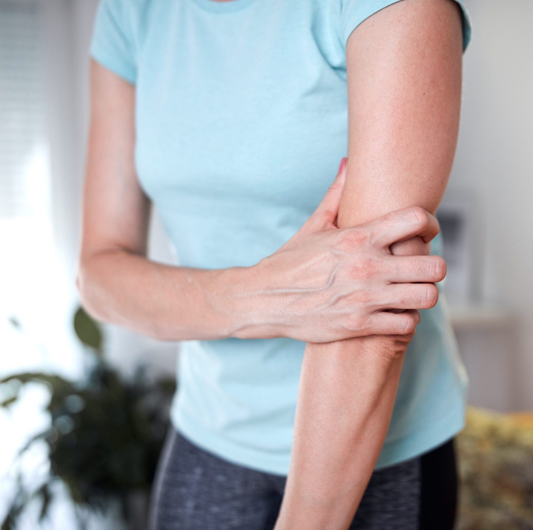 A woman holding her arm, in pain or discomfort.