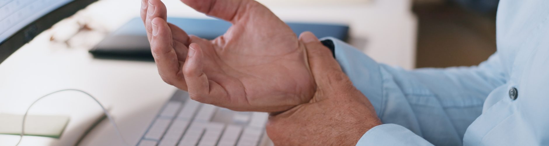 A man holding his right wrist with his left hand in discomfort.