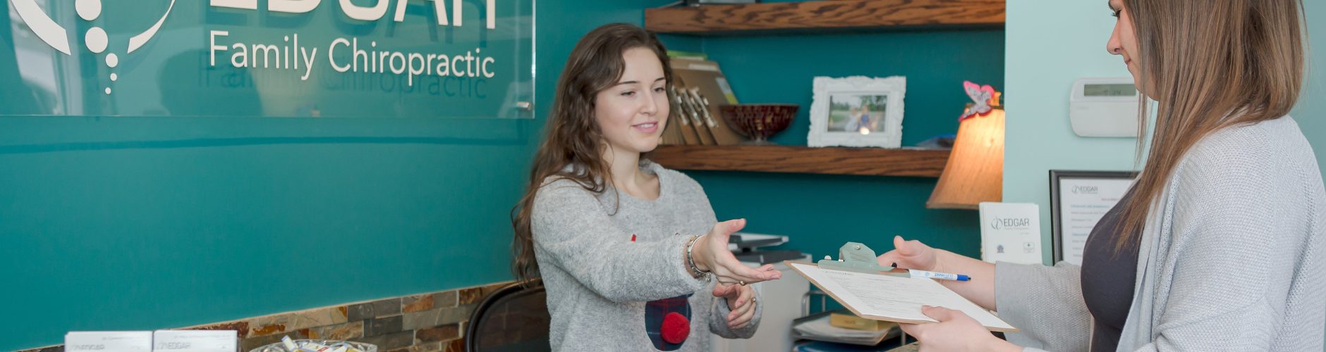 A receptionist being handed a clipboard with information by a client.