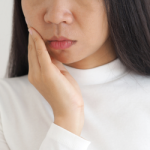 Woman having a jaw pain (TMJ).